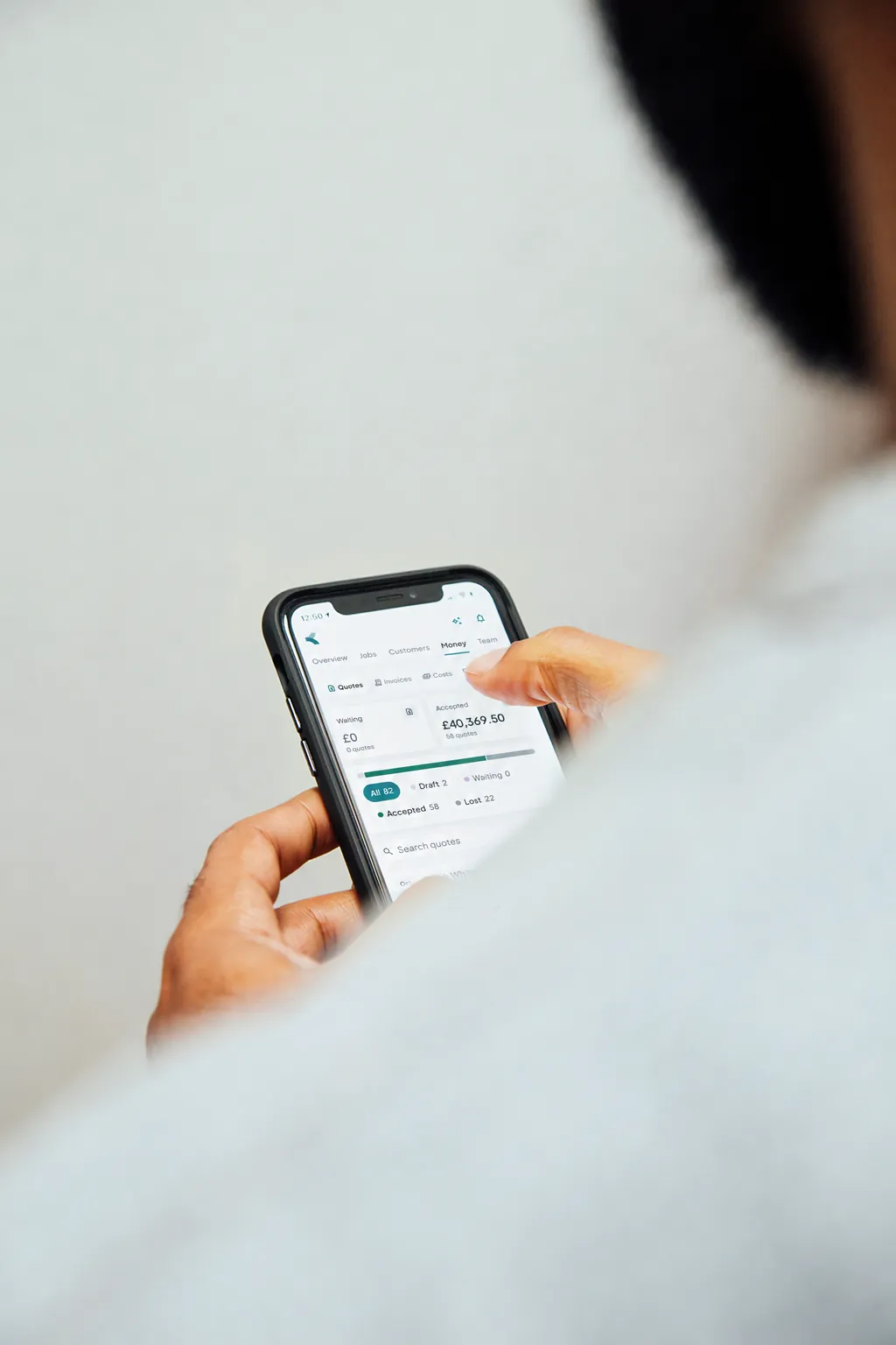 A hand holding a phone showing quotes in Kitso for Business